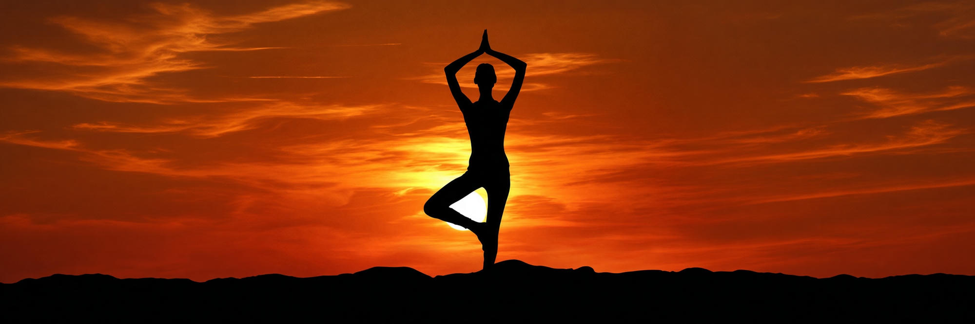 Silhouette practicing yoga at sunset
