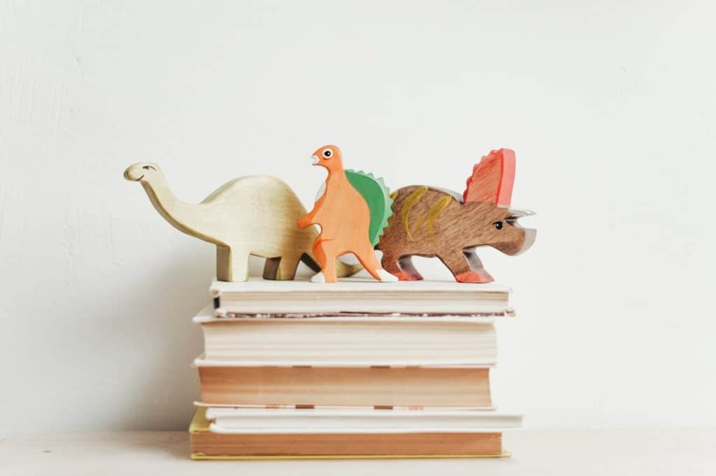 stack of books with three dinosaurs on top